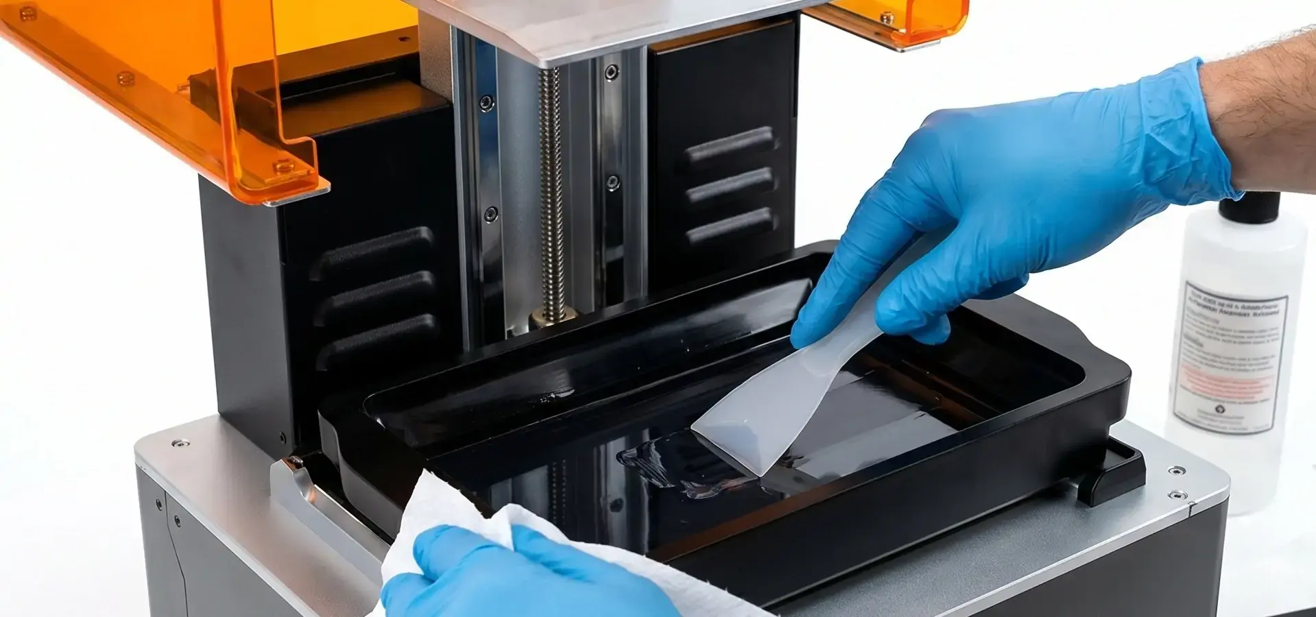 Technician cleaning build plate and resin vat of a Desktop 3D printer